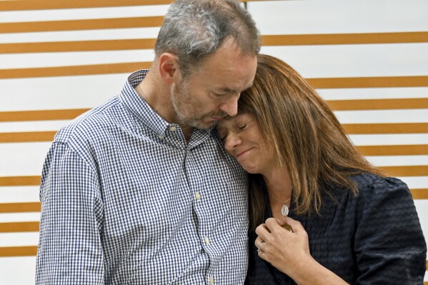 FILE - Simon and Sally Glass comfort each other during an emotional news conference about the death of their son, Christian Glass, Sept. 13, 2022, in Denver. Prosecutors on Wednesday, April 24, 2024, urged jurors to convict a former Colorado sheriff's deputy of murder and other charges for shooting and killing Christian Glass, a 22-year-old man in some kind of crisis, after they say the deputy needlessly escalated a standoff with him. (AP Photo/Thomas Peipert, File)
