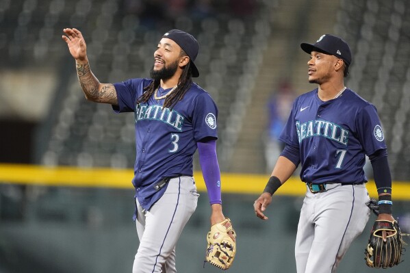 Seattle Mariners shortstop J.P. Crawford, left, and second baseman Jorge Polanco celebrate after the second game of a baseball doubleheader against the Colorado Rockies Sunday, April 21, 2024, in Denver. (AP Photo/David Zalubowski)