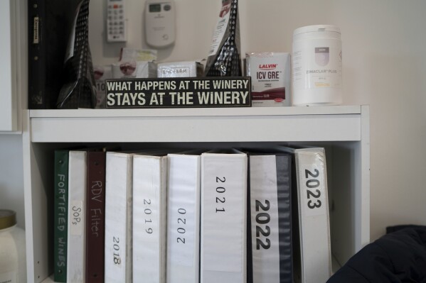 A sign that reads, "What happens at the winery stays at the winery," sits on a shelf in the head winemaker's office at Fox Run Vineyards, Friday, March 21, 2025, in Penn Yan, N.Y. (Natasha Kaiser via AP)