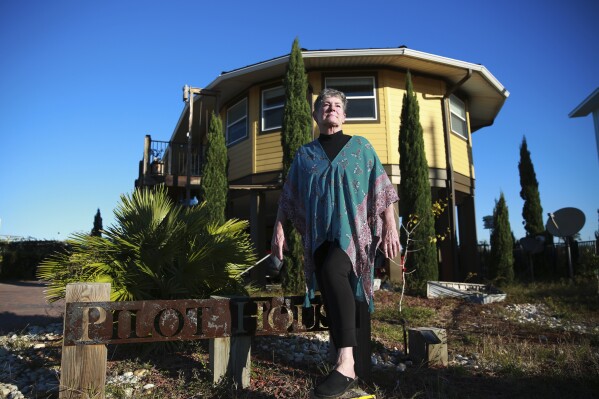 Bonny Paulson stands in front of her home in Mexico Beach, Fla. on Thursday, Oct. 19, 2023. The hurricane resistant house, designed by Deltec, was one of the few remaining structures left after Hurricane Michael hit the area in 2018. Some developers are building homes like Paulson's with an eye toward making them more resilient to the extreme weather that's increasing with climate change, and friendlier to the environment at the same time. (AP Photo/Laura Bargfeld)
