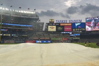Yankee Stadium staff set up a tarp on the field as it rains before a baseball game between the New York Yankees and the Toronto Blue Jays, Friday, Aug. 2, 2024, in New York. (AP Photo/Pamela Smith)