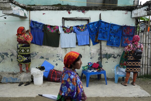 Women display traditional dresses for sale to tourists in Gardi Sugdub Island, part of the San Blas archipelago off Panama's Caribbean coast, Sunday, May 26, 2024. Due to rising sea levels, about 300 Guna Indigenous families will relocate to new homes, built by the government, on the mainland. (AP Photo/Matias Delacroix)