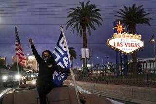 FILE - In this Nov. 7, 2020, file photo, Socorro Ulloa, a supporter of then-President-elect Joe Biden and Vice President-elect Kamala Harris, carries flags while riding in the back of a limousine in Las Vegas. Nevada lawmakers have passed a bill aiming to make the state the first to weigh in on the 2024 presidential primary contests. The move on Sunday, May 30, 2021, upends decades of political tradition and is likely to prompt pushback from other early states that want to retain their places in the calendar. Nevada's bill still needs to be approved by Democratic Gov. Steve Sisolak to become law, and it also requires the backing of the national parties to make the change for the 2024 calendar. (AP Photo/Jae C. Hong, File)