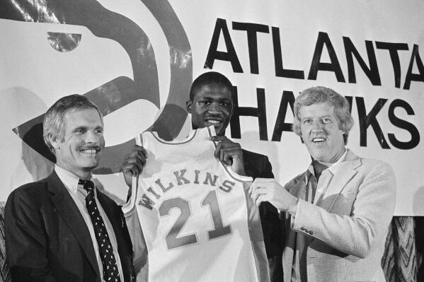 FILE - Dominique Wilkins, all time leading scorer at the University of Georgia, holds his Atlanta Hawks jersey flanked by coach Kevin Loughery, right, and owner Ted Turner on Sept. 4, 1982, in Atlanta. (AP Photo/Joe Holloway, File)