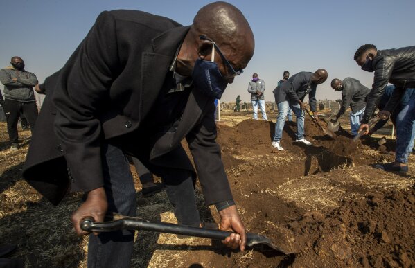 Mourners shovel earth into the grave of the late Duduzile Margaret Mbonane who died from COVID-19, during her funeral in Thokoza east of Johannesburg, South Africa, Thursday, July 23, 2020. Mbonane died just a month before her retirement, her husband said. Those on the front lines have been hit hard: The World Health Organization said Thursday more than 10,000 health workers have been infected in its African region, which is largely sub-Saharan Africa. (AP Photo/Themba Hadebe)
