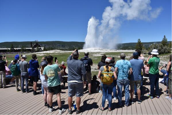 The Old Faithful geyser erupts and shoots water and steam into the air as tourists watch and take photos in Yellowstone National Park, Wyo., Wednesday, 22, 2022.  (AP Photo/Matthew Brown)