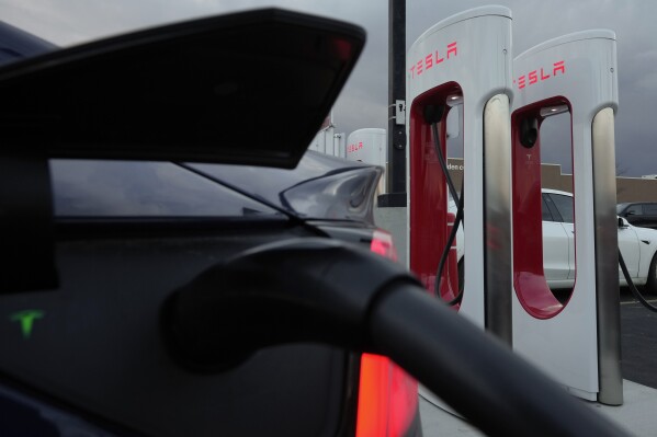 FILE - A vehicle charges at a Tesla Supercharger station in Detroit, Nov. 16, 2022. Owners of Ford electric vehicles can now use much of Tesla's charging network in the U.S. and Canada, but there's a hitch: they'll need to get an adapter that Ford will provide for free, although the company won't start shipping those until the end of March 2024. (AP Photo/Paul Sancya, File)