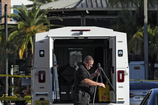 A Tampa police officer opens a tripod in the Ybor City section of Tampa, Fla., after a shooting early Sunday, Oct. 29, 2023. A fight between two groups turned deadly in a shooting during Halloween festivities. (AP Photo/Chris O'Meara)