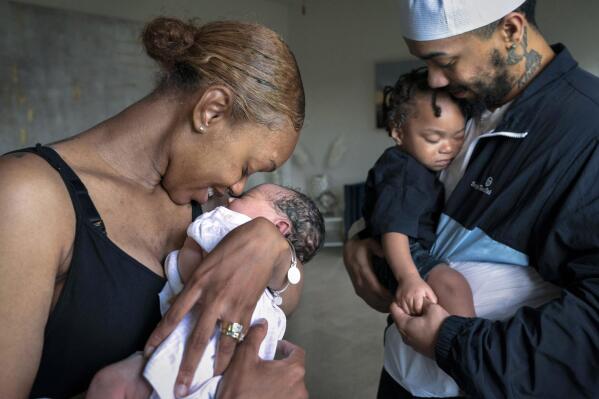 Aaliyah Wright, 25, of Washington, nuzzles her newborn daughter Kali, as her husband Kainan Wright, 24, of Washington, holds their son Khaza, 1, as he falls asleep, during a visit to the children's grandmother in Accokeek, Md., Tuesday, Aug. 9, 2022. A landmark social program is being pioneered in the nation’s capital. Coined “Baby Bonds,” the program is designed to narrow the wealth gap. The program would provide children of the city’s poorest families up to $25,000 when they reach adulthood. (AP Photo/Jacquelyn Martin)