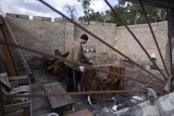 Yuriy Musienko, 45, works in a burned car garage near his mother's house in Moshchun, near Kyiv, Ukraine, Tuesday, Oct. 10, 2023. Many Ukrainians are expecting the same or worse this coming winter and have spent months preparing, including collecting firewood and buying generators. (AP Photo/Alex Babenko)