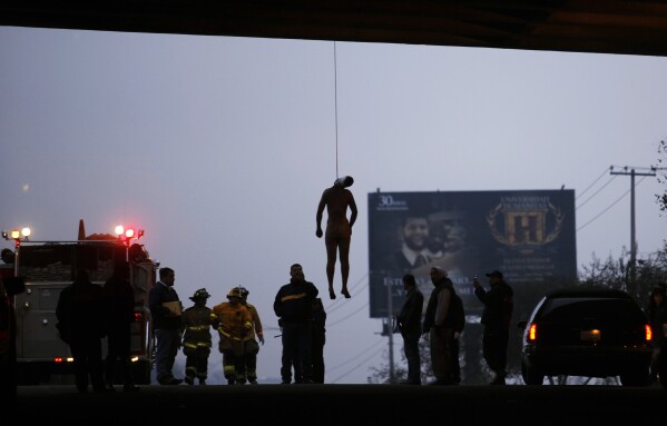 FILE - The body of an unidentified beaten and mutilated man hangs from his neck under a bridge on the old Rosarito Highway, in Tijuana, Mexico, Oct. 9, 2009. Tijuana, with a population of over 2.1 million, regularly sees around 2,000 murders annually, and has done so for years. (AP Photo/Guillermo Arias, File)