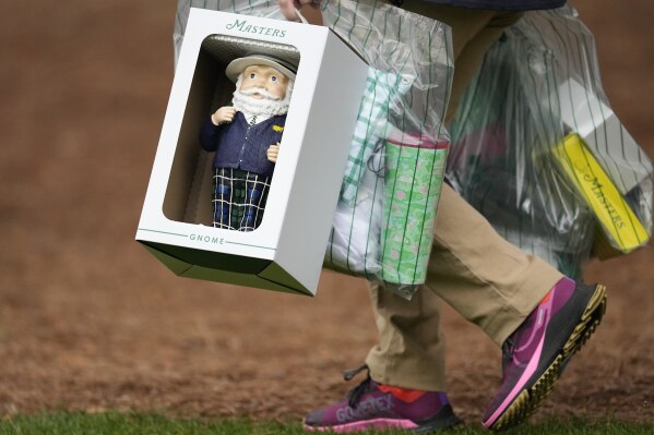 A patron carries a Masters gnome, a one-foot high ceramic figurine, during a practice round in preparation for the Masters golf tournament at Augusta National Golf Club Tuesday, April 9, 2024, in Augusta, Ga. (AP Photo/George Walker IV)