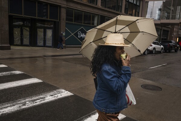 Shawn Bowie enjoyed her apple in a respite from thunderstorms and rain expected in the metro area including downtown Minneapolis, Minn., Monday, April 28, 2025. (Richard Tsong-Taatarii/Star Tribune via AP)