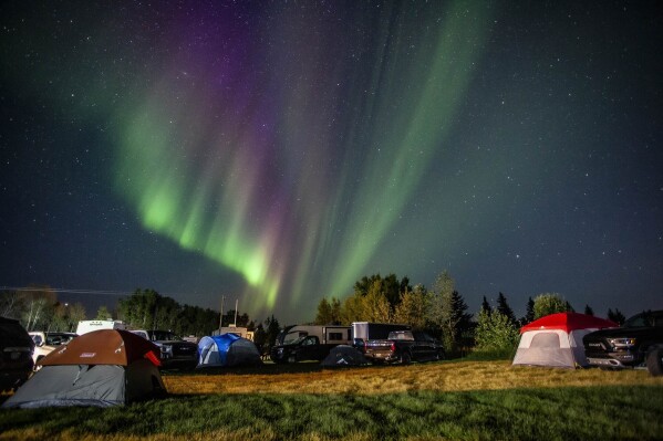 Evacuees from Yellowknife, territorial capital of the Northwest Territories, are greeted with the Aurora Borealis as they arrive to a free campsite provided by the community in High Level, Alberta, Aug. 18, 2023. (Jason Franson/The Canadian Press via AP)