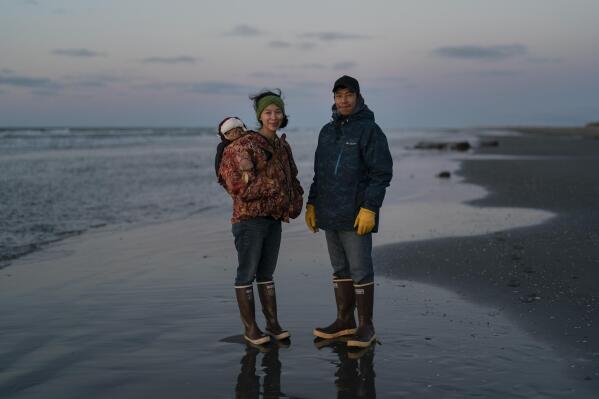 Ned Ahgupuk and girlfriend Kelsi Rock, stand for a photo with their 1-year-old son Steve Rock-Ahgupuk while strolling along the beach on the Arctic Ocean in Shishmaref, Alaska, Friday, Sept. 30, 2022. "We've been here all our lives," said Ahgupuk. He said climate change is a concern but he won't leave the island. "Everyone is like a big family caring for each other." (AP Photo/Jae C. Hong)
