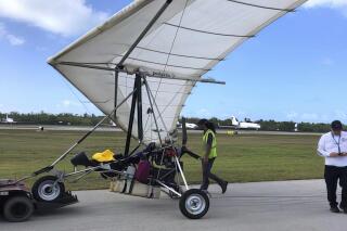 In this photo, provided by the Monroe County Sheriff's Office via the Florida Keys News Bureau, Key West International Airport personnel examine an ultralight aircraft that landed illegally at the airport carrying two Cuban men Saturday, March 25, 2023, in Key West, Fla. An airport spokesperson reported that both men were uninjured and were taken into custody by the Sheriff's Office. There were no interruptions in service and operations continue as normal, airport officials added. (Monroe County Sheriff's Office /the Florida Keys News Bureau via AP)