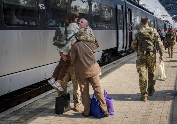 A Ukrainian serviceman hugs his wife and the daughter at the railway station in Sloviansk, Donetsk region, Ukraine on Tuesday, Sept. 12, 2023. The train that runs from Ukraine's capital, Kyiv, to the city of Kramatorsk in the east stands apart from others in Ukraine. It is shrouded in solemn silence as passengers anticipate their final destination — in front-line areas where battles rage between Ukrainian and Russian forces. (AP Photo/Hanna Arhirova)