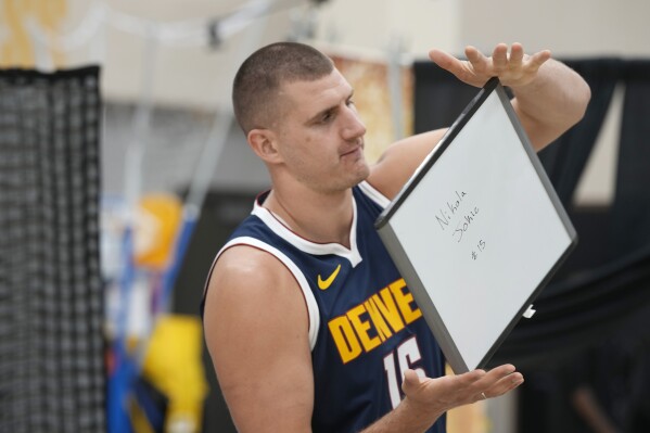 Denver Nuggets center Nikola Jokic spins a board with his name on it for identification purposes during the NBA basketball team's media day on Monday, Oct. 2, 2023, in Denver. (AP Photo/David Zalubowski)