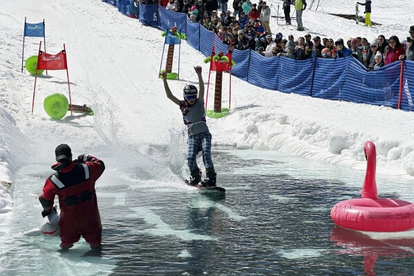 A snowboarder participates in a pond skimming event at Gunstock Mountain Resort, Sunday, April 7, 2024, in Gilford, N.H. The wacky spring tradition is happening this month at ski resorts across the country and is often held to celebrate the last day of the skiing season. (AP Photo/Nick Perry)
