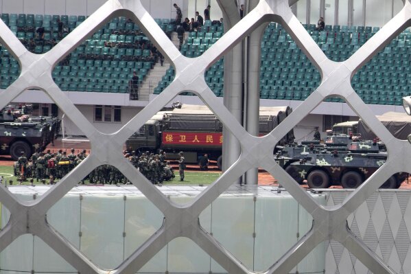 Chinese paramilitary policemen go through drills near the slogan for "Protect the People" at the Shenzhen Bay Stadium in Shenzhen in Southern China's Guangdong province on Sunday, Aug. 18, 2019. A spokesman for China's ceremonial legislature has condemned statements from U.S. lawmakers supportive of Hong Kong's pro-democracy movement. (AP Photo/Ng Han Guan)