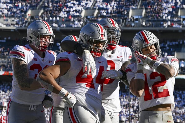 FILE - Ohio State defensive end J.T. Tuimoloau (44) celebrates with his teammates Jack Sawyer (33), Zach Harrison (9) and Lathan Ransom (12) after returning an interception for a touchdown during the fourth quarter of an NCAA college football game against Penn State, on Oct. 29, 2022, in State College, Pa. Ohio State is No. 3 in The Associated Press preseason Top 25 poll released Monday, Aug. 14, 2023. (AP Photo/Barry Reeger, File)