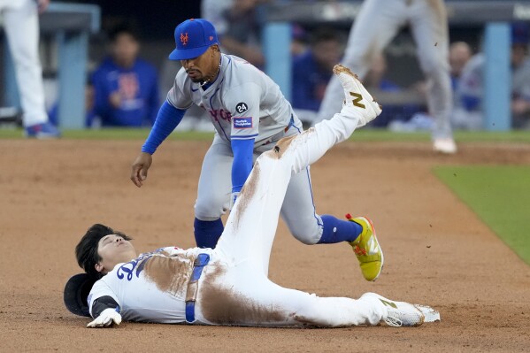 CORRECTS TO CLARIFY OHTANI WAS OUT IN THE PLAY - Los Angeles Dodgers' Shohei Ohtani gets caught stealing by New York Mets shortstop Francisco Lindor during the second inning in Game 1 of a baseball NL Championship Series, Sunday, Oct. 13, 2024, in Los Angeles. (AP Photo/Mark J. Terrill)