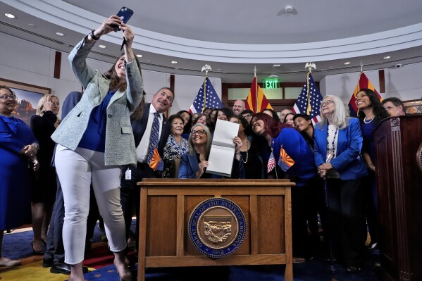 Ariz.. Rep. Stephanie Stahl Hamilton, takes a selfie with Arizona Gov. Katie Hobbs, after Hobbs signed the repeal of the Civil War-era near-total abortion ban to Thursday, May 2, 2024, at the Capitol in Phoenix. Democrats secured enough votes in the Arizona Senate to repeal the ban on abortions that the state's highest court recently allowed to take effect. (AP Photo/Matt York)
