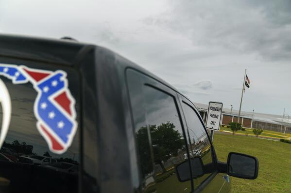 FILE - A pickup truck with a Confederate flag-themed decal is parked outside the Reception and Medical Center, the state's prison hospital where new inmates are processed, in Lake Butler, Fla., Friday, April 16, 2021. According to public documents and interviews with a dozen inmates and current and former employees in the nation’s tenth largest prison system, Florida prison guards openly tout associations with white supremacist groups to intimidate inmates and Black colleagues, a persistent practice that goes unpunished and is allowed to fester in prisons throughout the U.S. (AP Photo/David Goldman, File)
