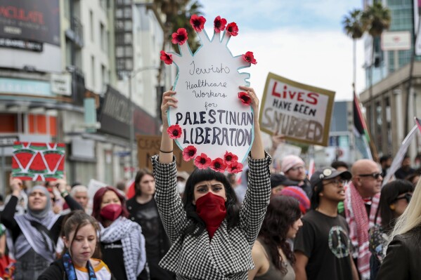 A protester holds a poster during a demonstration in support of Palestinians calling for a ceasefire in Gaza as the 96th Academy Awards Oscars ceremony is held nearby, Sunday, March 10, 2024, in the Hollywood section of Los Angeles. (AP Photo/Etienne Laurent)