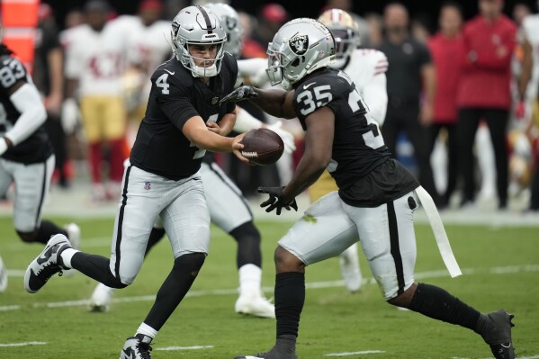 Las Vegas Raiders quarterback Aidan O'Connell (4) hands off to running back Zamir White (35) during the first half of an NFL preseason football game against the San Francisco 49ers, Sunday, Aug. 13, 2023, in Las Vegas. (AP Photo/John Locher)