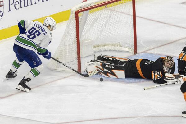 Philadelphia Flyers goaltender Carter Hart (79) dives on a shot on goal by Vancouver Canucks center Elias Pettersson as Andrei Kuzmenko (96) moves in during the second period of an NHL hockey game, Saturday, Oct. 15, 2022, in Philadelphia. (AP Photo/Laurence Kesterson)