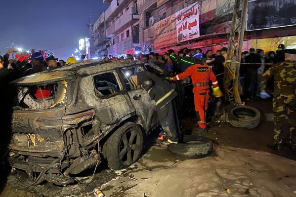 Civil defense members gather at the site of a burned vehicle targeted by a U.S. drone strike in east Baghdad, Iraq, Wednesday, Feb. 7, 2024. (AP Photo/Hadi Mizban)