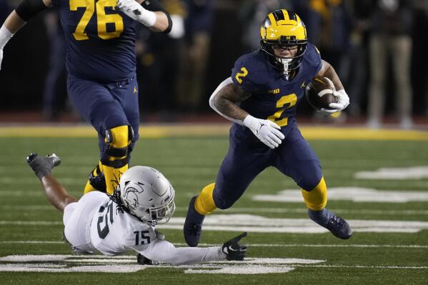Michigan running back Blake Corum (2) escapes Michigan State safety Angelo Grose (15) in the first half of an NCAA college football game in Ann Arbor, Mich., Saturday, Oct. 29, 2022. (AP Photo/Paul Sancya)