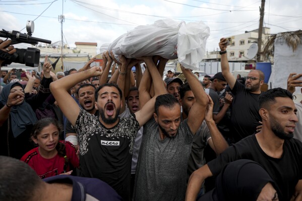 FILE - Palestinians mourn as they carry the body of a relative killed in the Israeli bombardment of the Gaza Strip at a hospital in Deir al-Balah, Oct. 8, 2024. (AP Photo/Abdel Kareem Hana, File)