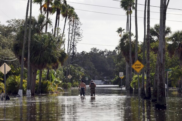 Men walk down a street flooded by Hurricane Helene in the Shore Acres neighborhood Sept. 27, 2024, in St. Petersburg, Fla. (AP Photo/Mike Carlson, File)