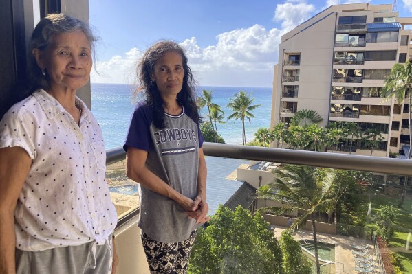 Evangeline Balintona, left, and Elsie Rosales pose on the balcony of a hotel room in Lahaina, Hawaii, on Thursday, Aug. 31, 2023. They are among the many Filipinos who work as Maui hotel housekeepers living temporarily in hotel rooms after losing their homes to a deadly fire. (AP Photo/Jennifer Sinco Kelleher)