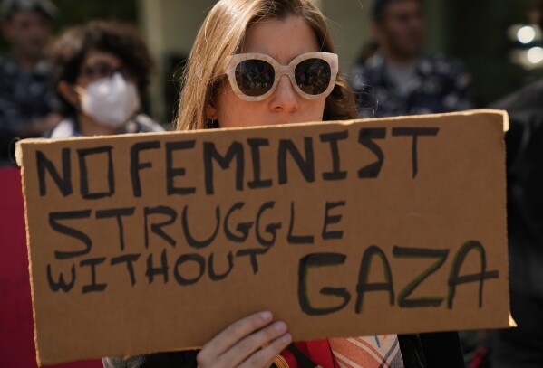 A Lebanese woman holds a placard, as she attends a protest to support the Palestinian women on the International Women's Day outside the office of a U.N. organisation, in Beirut, Lebanon, Friday, March 8, 2024. The U.N. agency for Palestinian refugees says about 9,000 women have been killed in the Gaza Strip since the Israel-Hamas war began five months ago. (AP Photo/Hussein Malla)