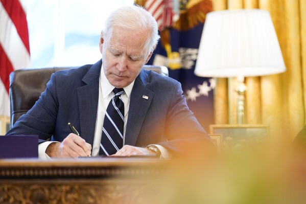 FILE - President Joe Biden signs the American Rescue Plan, a coronavirus relief package, in the Oval Office of the White House, March 11, 2021, in Washington. Federal officials estimate that local governments now have spending plans in place for most of the money they received under a prominent pandemic relief law. In some cases, it's hard to know exactly how the money is being used, because some governments haven't supplied details about their projects. (AP Photo/Andrew Harnik, File)
