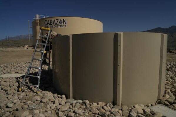 Glenn Chavez tests a newly installed Heli-Hydrant, a small, open tank that helicopters can rely on to get water faster for urban fires, Friday, April 11, 2025, in Cabazon, Calif. (AP Photo/Brittany Peterson)