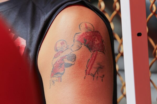 A Nebraska fan displays a tattoo rendering of cancer patient Jack Hoffman, left, who became famous when he scored a 2013 touchdown during spring scrimmage, during NCAA college football fan day in Lincoln, Neb., Aug. 2, 2013. (AP Photo/Nati Harnik, File)