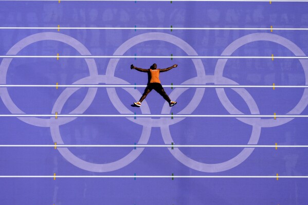 An athlete from the Netherlands lays on the track after a practice session at the 2024 Summer Olympics, Thursday, Aug. 1, 2024, in Saint-Denis, France. (AP Photo/David J. Phillip)