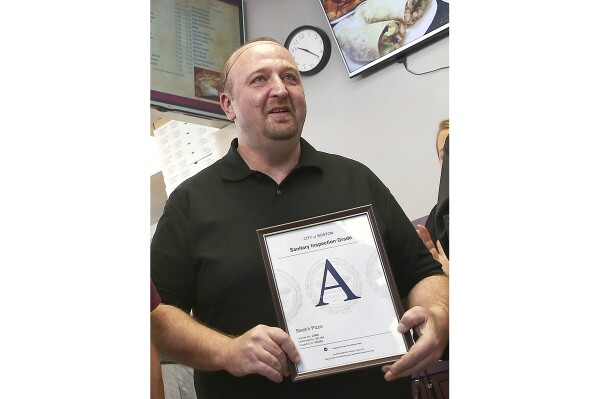 FILE - Stavros Papantoniadis, owner of Stash's Pizza, a Boston sanitary grade certificate after inspection by the Health Division of the Inspectional Services Department on Nov 2, 2016, in Boston. Papantoniadis was convicted Friday, June 7, 2024, of forced labor charges following a nine-day jury trial. (Pat Greenhouse/The Boston Globe via AP, File)