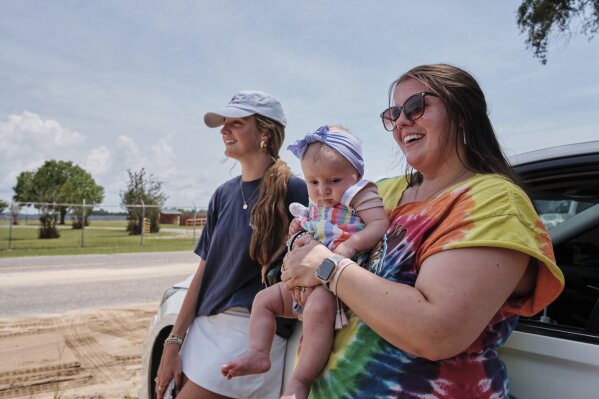 Fans Emma Touchstone, 17, left, and Kelsey Heath with her four-month-old daughter Maggie Fields wait for reality television star Todd Chrisley walks out of the Federal Prison Camp, Wednesday, May 28, 2025, in Pensacola, Fla. (AP Photo/Dan Anderson)