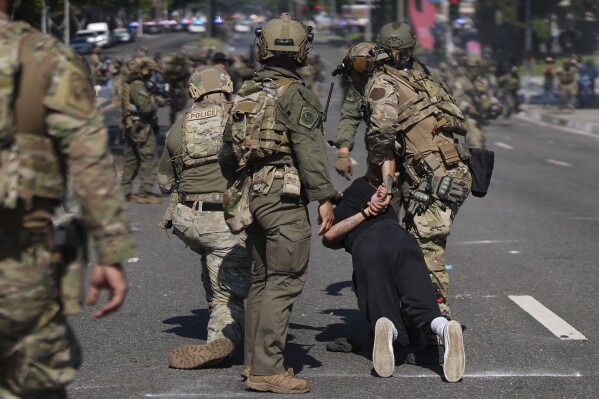 Police detain a man during a protest in the Paramount section of Los Angeles, Saturday, June 7, 2025, after federal immigration authorities conducted operations. (AP Photo/Eric Thayer)