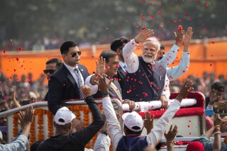 Flower petals are thrown to welcome the Indian Prime Minister Narendra Modi, wearing a waistcoat, as he arrives with Assam Chief Minister Himanta Bishwa Sarma, to his right, to address a public rally in Guwahati, India, Sunday, Feb. 4, 2024. (AP Photo/Anupam Nath)