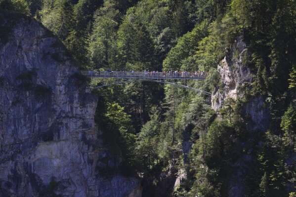 Tourists stand on the Marienbr'cke bridge, near the Neuschwanstein castle, in Schwangau, Germany, Thursday, June 15, 2023. Authorities say an American man has been arrested in Germany after allegedly assaulting two tourists he met near Neuschwanstein castle. The attack, which occurred on Wednesday, left one of the women dead. Police said Thursday that the 30-year-old man met the two women on a hiking path and lured them onto a trail. They said the man then “physically attacked” the younger woman. (Frank Rumpenhorst/dpa via AP)