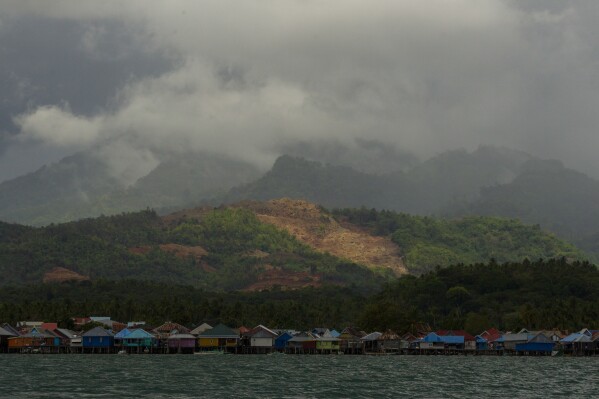 A nickel mine is visible on top of a hill above a village on Kabaena Island, Indonesia, Thursday, Nov. 14, 2024. (AP Photo/Yusuf Wahil)