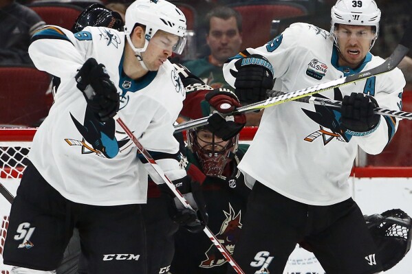 FILE - San Jose Sharks center Tomas Hertl, left, and center Logan Couture (39) try to redirect the puck in front of Arizona Coyotes goaltender Adin Hill, center, during the second period of an NHL hockey game Dec. 8, 2018, in Phoenix. Hertl and Couture. The two centermen are among the last remaining ties to the team that made it to the Western Conference final in 2019. (AP Photo/Ross D. Franklin, File)