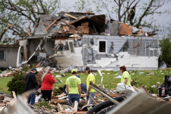 People sort through the remains of a home damaged by a tornado Tuesday, May 21, 2024, in Greenfield, Iowa. (AP Photo/Charlie Neibergall)