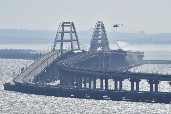 A helicopter drops water to stop fire on Crimean Bridge connecting Russian mainland and Crimean peninsula over the Kerch Strait, in Kerch, Saturday, Oct. 8, 2022. Russian authorities say a truck bomb has caused a fire and the collapse of a section of a bridge linking Russia-annexed Crimea with Russia. The bridge is a key supply artery for Moscow's faltering war effort in southern Ukraine. (AP Photo)